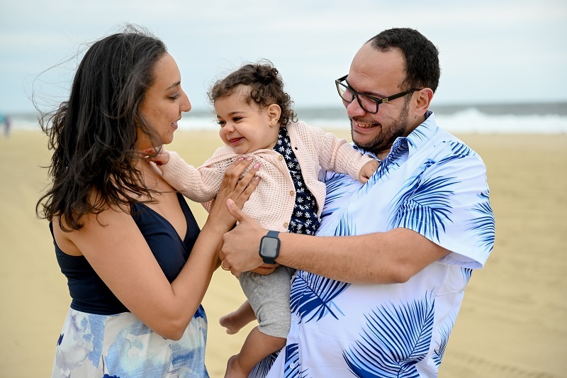 Dr. Andrew Habib, his wife and new baby smiling on the beach.