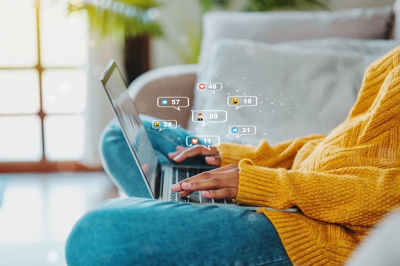 Woman using a laptop on the couch, on social media sites with notifications popping up.