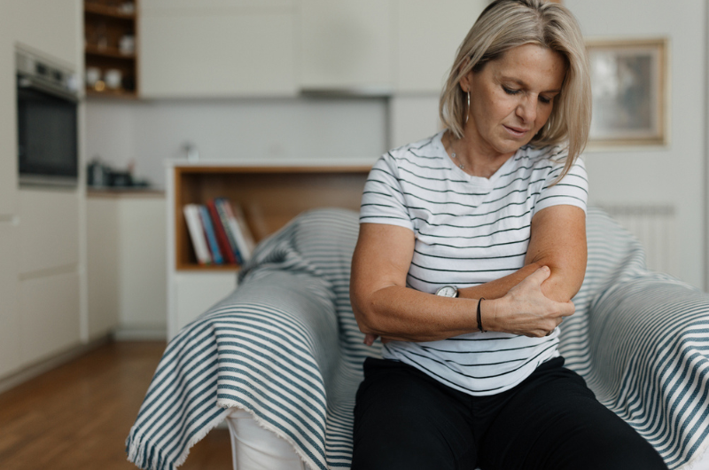 Middle-aged adult woman having elbow pain.